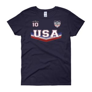 May include: A navy blue women's t-shirt with a white, red, and blue USA graphic. The graphic includes the number 10 and a soccer ball.