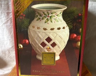 May include: A cream ceramic holiday fragrance warmer with a lattice design. The top has a floral pattern with holly leaves and berries. The box reads "Holiday Fragrance Warmer" and "Sunny for the Holidays."