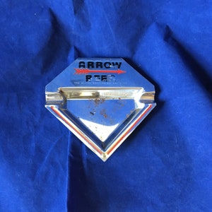 May include: A silver diamond-shaped ashtray with a red and black logo that reads "Arrow Beer The Globe Brewing Co. Baltimore, Md."