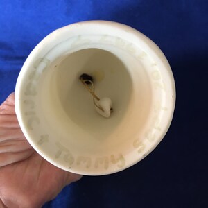 May include: White ceramic bell with a gold-colored clapper. The bell has the words "Our Family" written on the inside.
