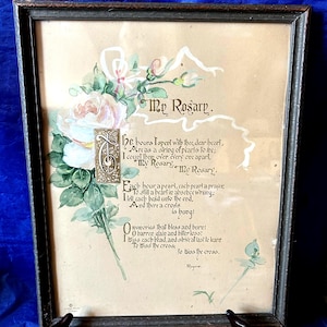May include: Framed artwork featuring a poem titled "My Rosary" with floral watercolor accents. The artwork includes a dark wooden frame and a beige background. The poem is written in elegant script with decorative elements.