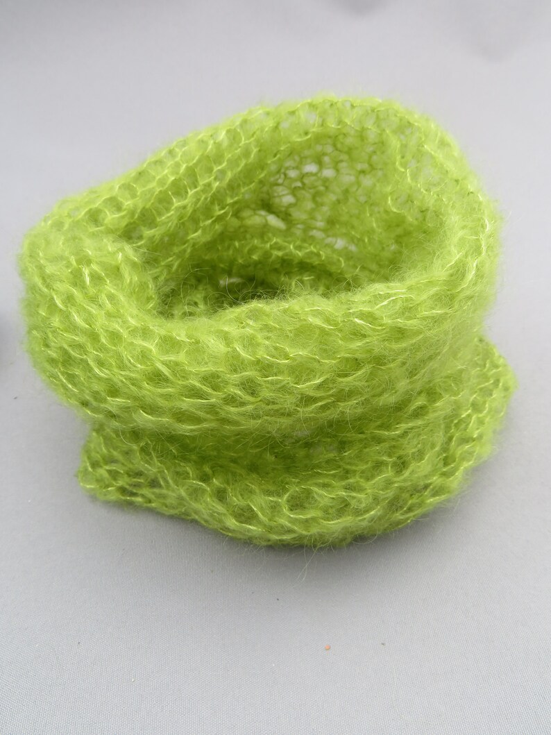 May include: A lime green knitted cowl made from a soft, fuzzy yarn.