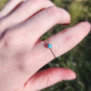 Op de afbeelding: Een zilveren ring met een kleine turquoise steen in het midden.