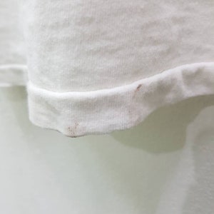 Puede incluir: Camiseta blanca con una ligera mancha marr&oacute;n en el dobladillo inferior.