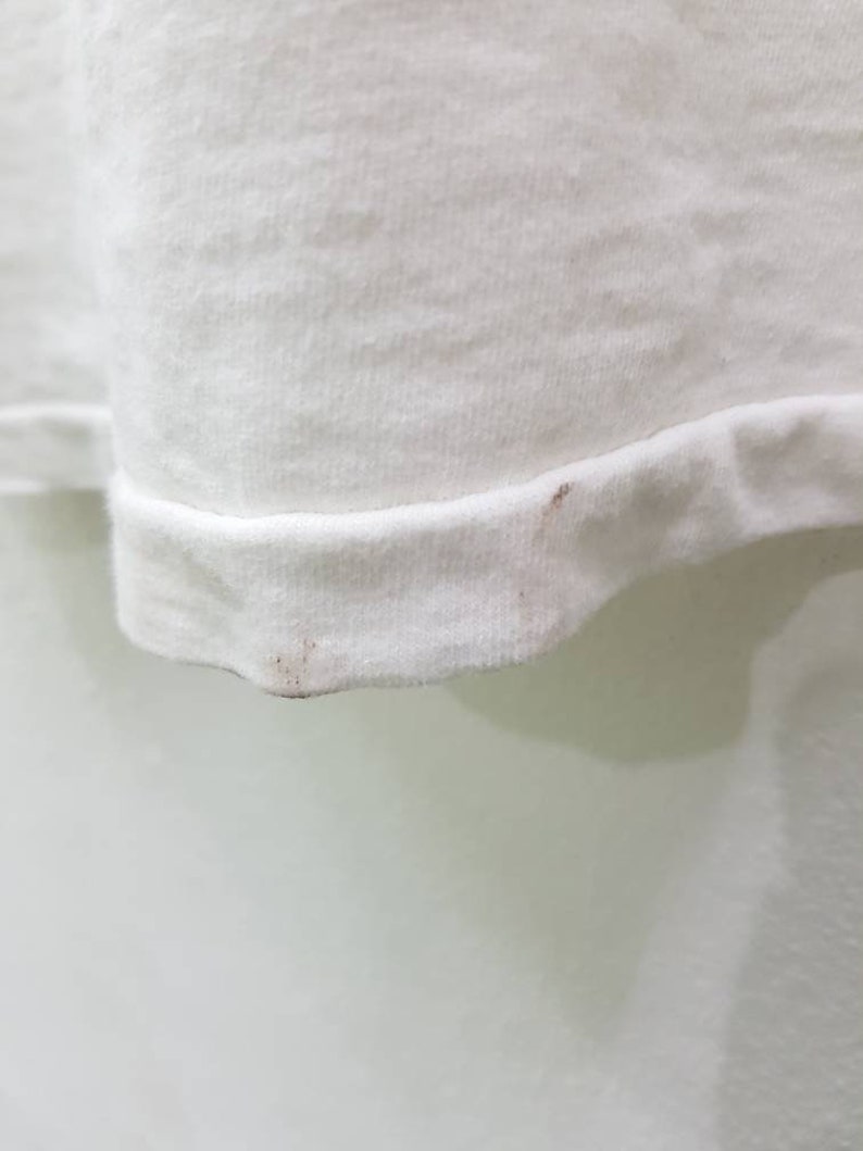 Puede incluir: Camiseta blanca con una ligera mancha marr&oacute;n en el dobladillo inferior.
