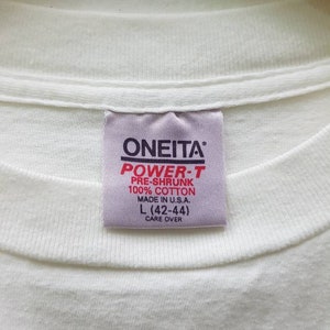 Puede incluir: Etiqueta blanca con texto negro que dice "ONEITA POWER-T PRE-SHRUNK 100% COTTON MADE IN U.S.A. L (42-44) CARE OVER"