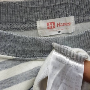 May include: Grey and white striped shirt with a Hanes label. The label says "Hanes" and "North Carolina, USA". The size is "M".