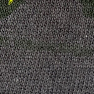 May include: Close-up of a dark gray fabric with a subtle texture. The fabric has a faint yellow pattern.