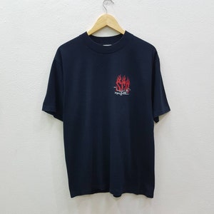 May include: Black t-shirt with a red and white graphic of a skull with flames and the text "SCA" on the front.