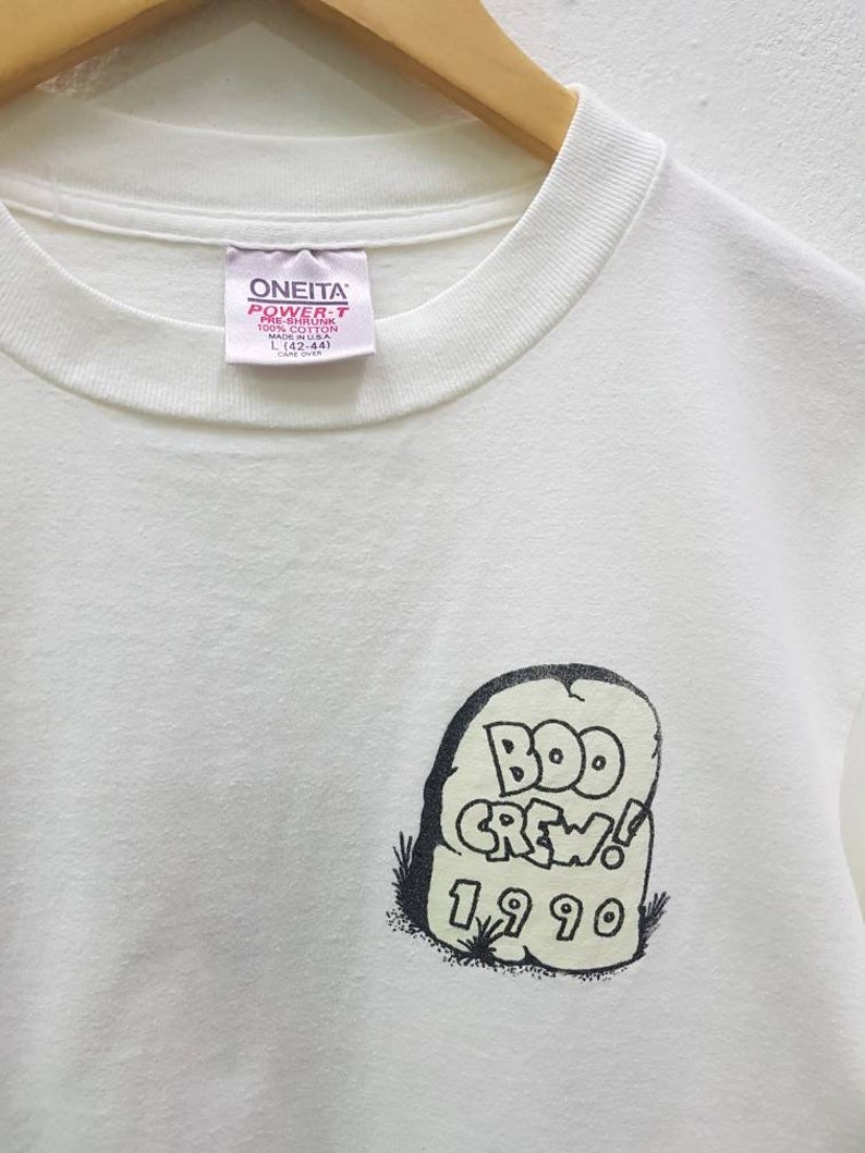Puede incluir: Camiseta blanca con un gr&aacute;fico en blanco y negro de una l&aacute;pida con el texto "BOO CREW! 1990". La camiseta tiene una etiqueta que dice "ONEITA POWER-T PRE-SHRUNK 100% COTTON MADE IN USA L (42-44) CARE OVER"