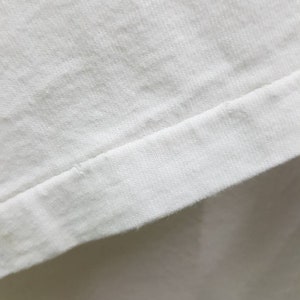 Puede incluir: Primer plano de una tela de algod&oacute;n blanca con una costura a lo largo del borde.