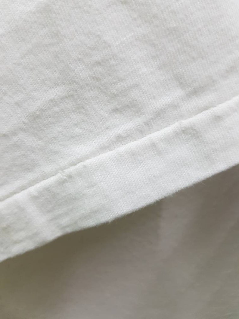 Puede incluir: Primer plano de una tela de algod&oacute;n blanca con una costura a lo largo del borde.