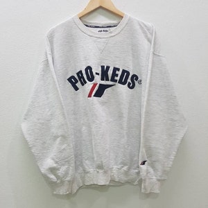 May include: A white sweatshirt with a navy blue and red embroidered logo that says "PRO-KEDS" on the front.