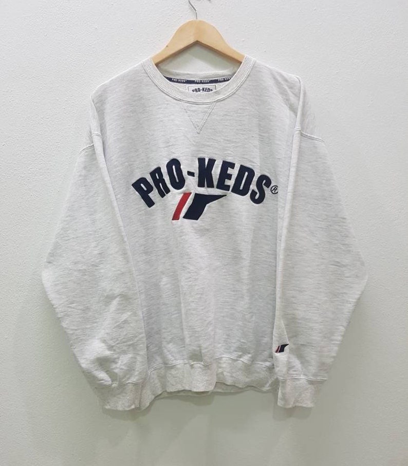 May include: A white sweatshirt with a navy blue and red embroidered logo that says "PRO-KEDS" on the front.