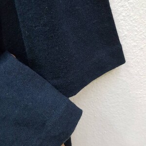 May include: Close-up of the navy blue fabric of a long-sleeved shirt. The fabric is soft and has a slight texture.
