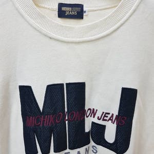 May include: White long-sleeve sweatshirt with a black and white embroidered logo that says "Michico London Jeans" and "Jeans" in a smaller font.