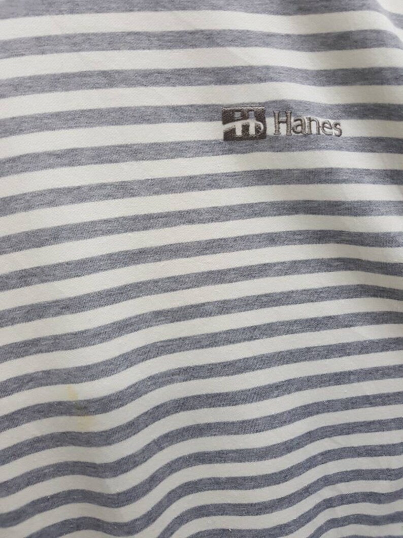 May include: White and grey striped t-shirt with a small Hanes logo embroidered on the front.