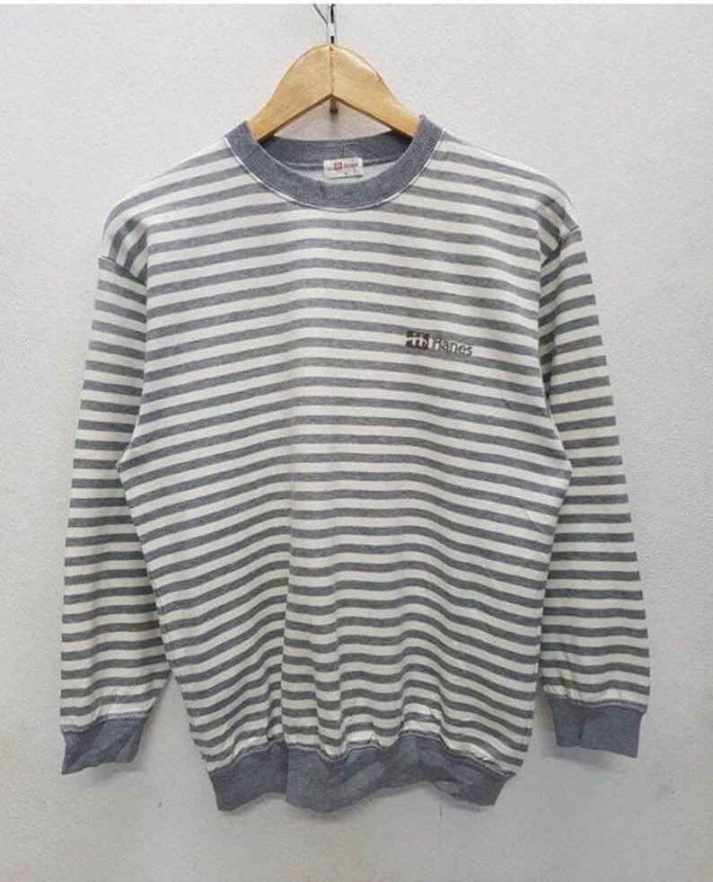 May include: Grey and white striped long-sleeved shirt with a Hanes logo on the front.