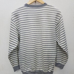 May include: A grey and white striped long-sleeved sweatshirt.