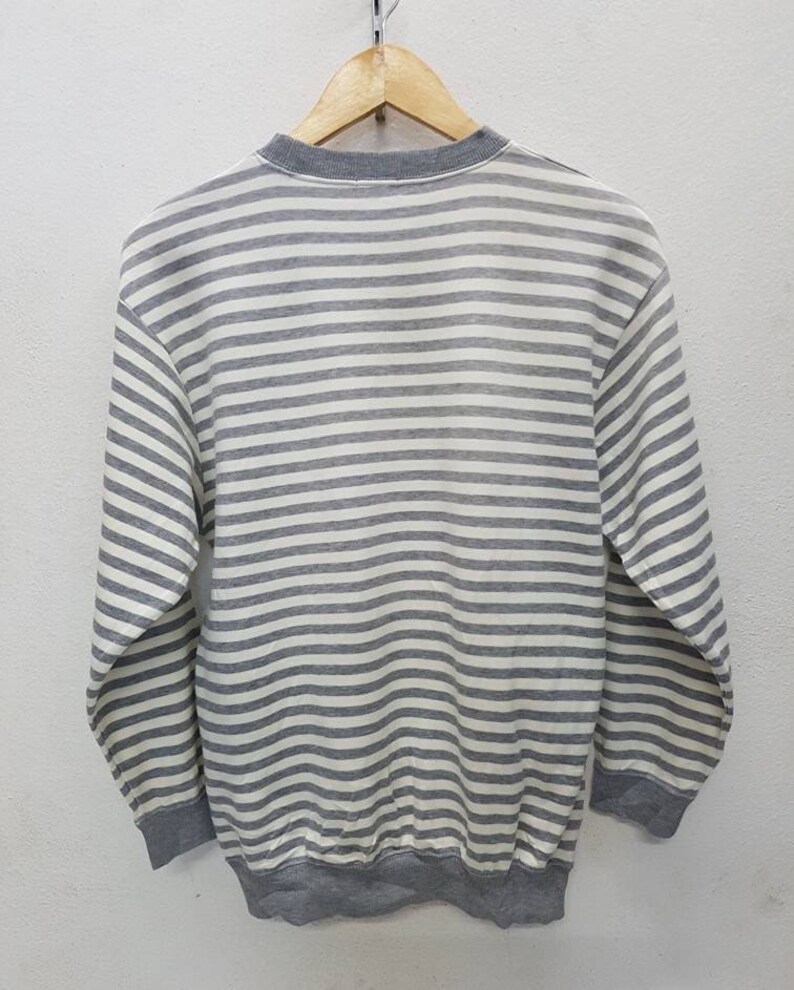 May include: A grey and white striped long-sleeved sweatshirt.