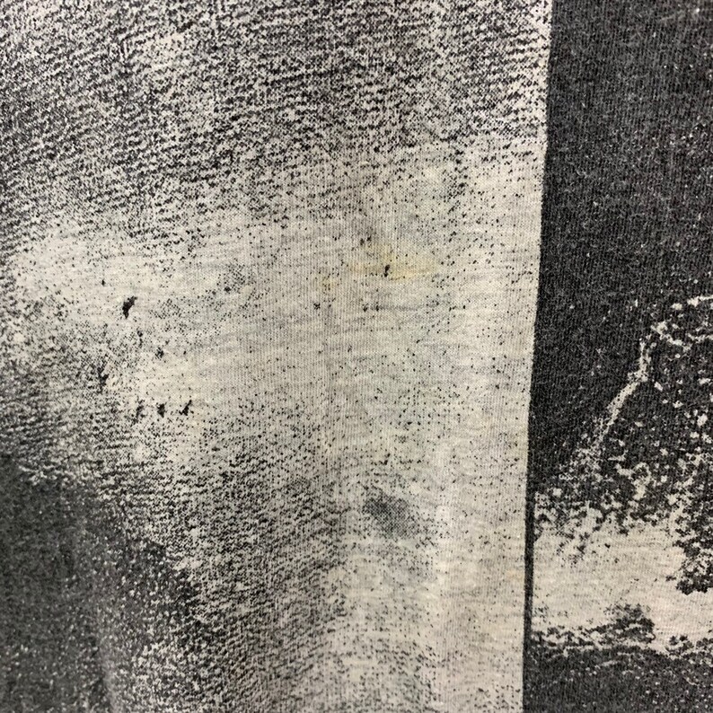 May include: Close-up of a black and white patterned fabric with a faded, white area. The fabric has a textured, woven appearance.
