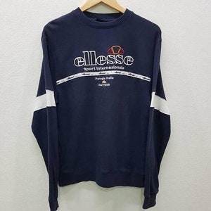 May include: A navy blue long-sleeved sweatshirt with white trim on the sleeves. The sweatshirt has a white embroidered logo that says "ellesse Sport Internazionale Perugia Italia Dal 1959".