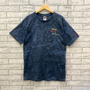 Peut inclure: Un t-shirt bleu foncé avec un imprimé graphique d'un motif de grille et le texte "Link Up/ Sync Up/ be the future".