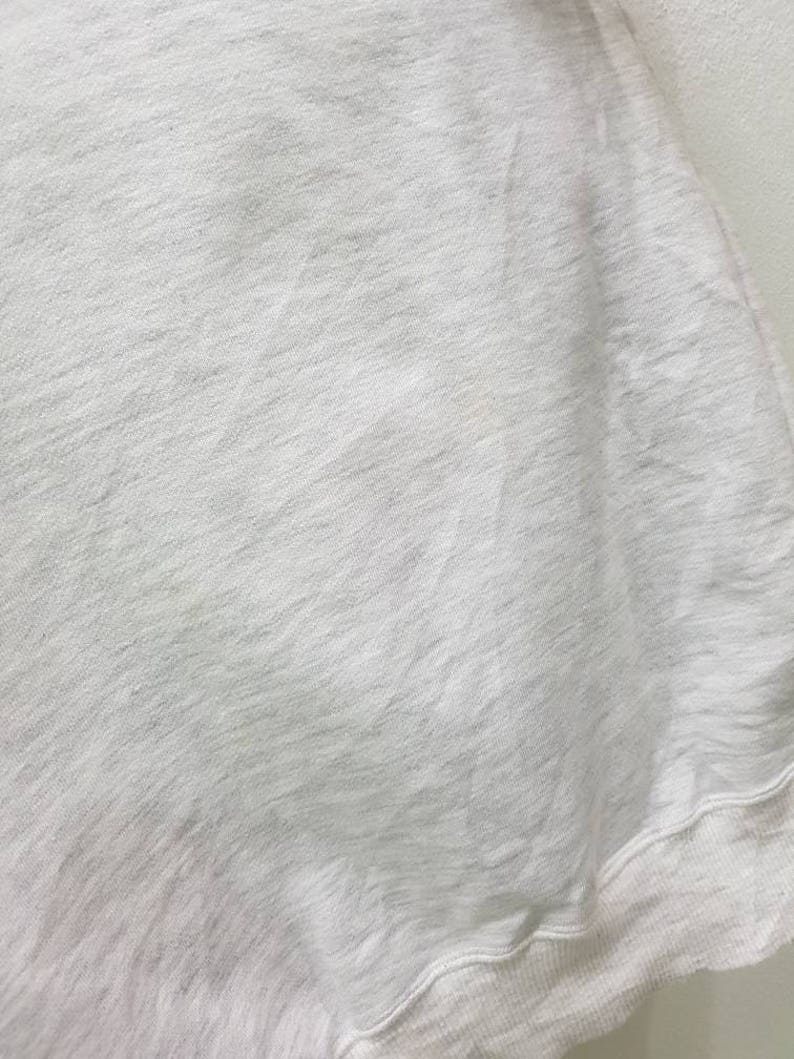 May include: A white sweatshirt with a soft, textured fabric. The sweatshirt has a ribbed hem and cuffs.