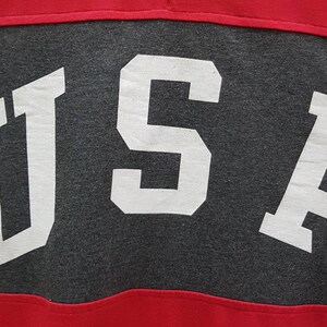 May include: A gray and red shirt with the word "USA" printed in white on the gray section.