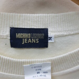 May include: White cotton sweatshirt with a black label that reads "MICHIKO LONDON JEANS" and a size tag that reads "M". The label also includes the text "C-GH1322", "日本製" (Japanese for "Made in Japan"), "綿 100%" (Japanese for "100% cotton"), and "ホテャ H9-06".