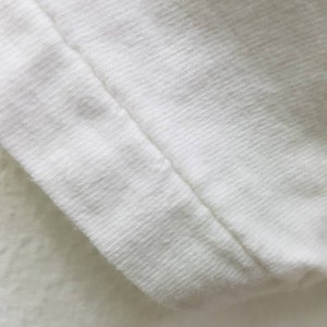 Puede incluir: Primer plano de una tela de algod&oacute;n blanca con una costura que recorre el borde.