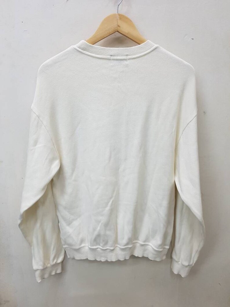 May include: A white long-sleeved sweatshirt with a crew neck.