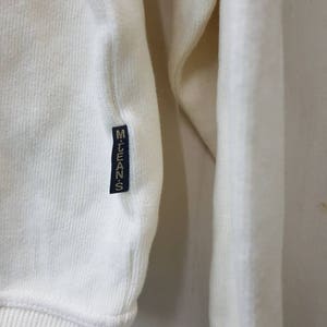 May include: White long-sleeve shirt with a ribbed texture and a black label that says "M.LEANS" on the left side.