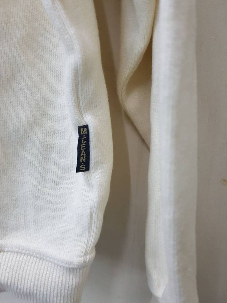 May include: White long-sleeve shirt with a ribbed texture and a black label that says "M.LEANS" on the left side.