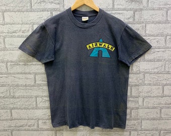 May include: A dark gray t-shirt with a blue and yellow Airwalk logo. The logo is a triangle with the word "Airwalk" written in yellow letters.