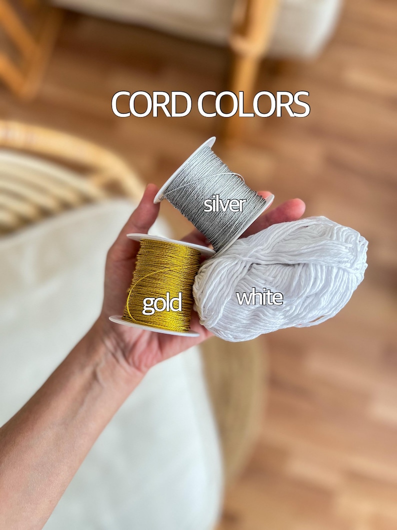 May include: Three spools of cord in gold, silver, and white. The spools are labeled with the corresponding colors. CORD COLORS is written above the spools.