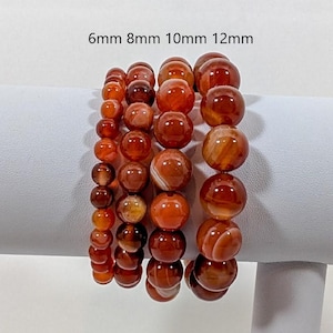 May include: Four carnelian gemstone bracelets with different bead sizes: 6mm, 8mm, 10mm, and 12mm. The bracelets are stacked on a white surface.