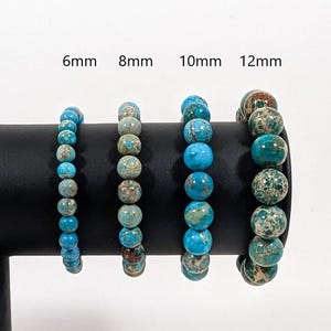 May include: Four turquoise blue and brown jasper bracelets with different bead sizes: 6mm, 8mm, 10mm, and 12mm.
