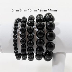 Peut inclure: Cinq bracelets en perles noires de différentes tailles. Les bracelets sont étiquetés 6 mm, 8 mm, 10 mm, 12 mm et 14 mm.