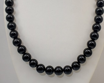 Puede incluir: Un collar de cuentas negras con cuentas redondas y brillantes.