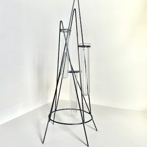 May include: Black metal geometric vase with three glass test tubes. The vase is designed to hold flowers or other small plants.