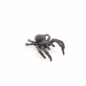 May include: A black plastic spider toy with eight legs. The spider is posed as if it is crawling.