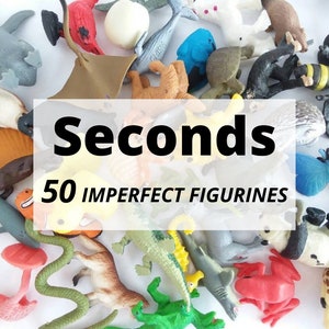 May include: A collection of 50 imperfect plastic animal figurines, including a blue whale, a green crocodile, a red frog, a yellow duck, a brown bear, a grey wolf, a pink flamingo, a green snake, a blue butterfly, and a bee. The figurines are all different sizes and shapes, and some have minor imperfections. The text "Seconds 50 Imperfect Figurines" is printed on a white background.