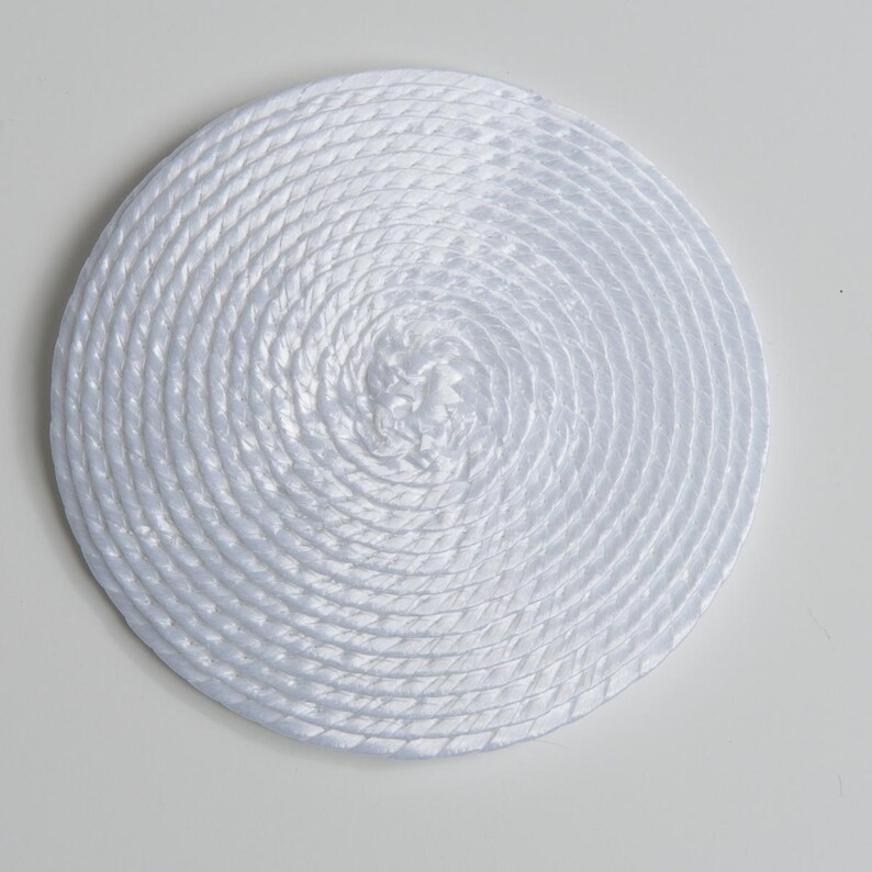 May include: A circular white coaster or mat constructed from a continuous, tightly coiled synthetic rope. The material features a smooth, glossy finish with a distinct braided texture that spirals outward from the center to the edge.