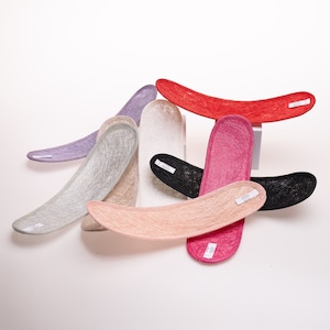 May include: A set of seven colorful, woven, crescent-shaped hats in various shades of pink, red, white, gray, and black.