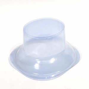 May include: A clear, light blue plastic hat-shaped container. The container has a wide, slightly curved brim and a cylindrical crown. The plastic is translucent, allowing light to pass through. The object is likely a protective cover or packaging.