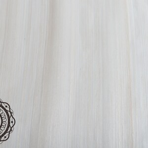 May include: A light-colored, textured background with vertical brushstrokes. A decorative circular emblem with the word "Zoria" in the center is in the lower left corner. The emblem is brown with a dotted border.