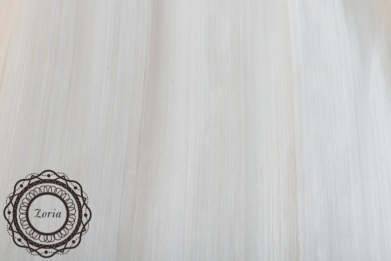 May include: A light-colored, textured background with vertical brushstrokes. A decorative circular emblem with the word "Zoria" in the center is in the lower left corner. The emblem is brown with a dotted border.