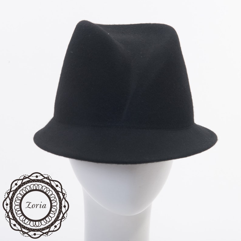 May include: A black felt fedora hat with a wide brim. The hat is on a white mannequin head.