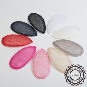 May include: Assortment of 10 teardrop-shaped hat bases in various colors, including black, white, red, pink, beige, and gray. The bases are made of a woven material and have a slightly rounded edge.